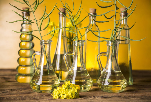 Seeds and rape flowers in bottles and carafes with rapeseed oil - Φωτογραφία, εικόνα