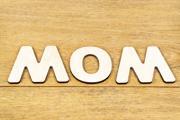 word mom of wooden letters on table - Fotoğraf, Görsel
