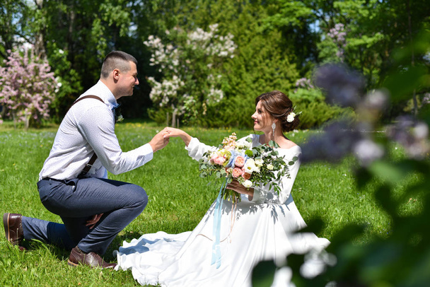 Bride and groom in a bouquet are walking in a green park - Foto, Bild