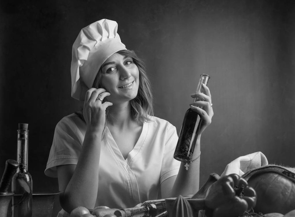  Young woman in a chef uniform with small bottle of olive oil. - Photo, Image