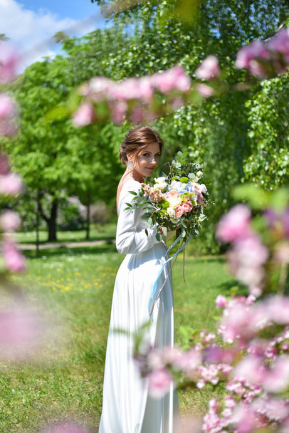 Bride with a bouquet of flowers in the summer park - Foto, Imagem