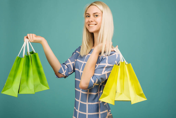 Damalı bluzlu mutlu kız alışveriş çantaları tutar - Fotoğraf, Görsel