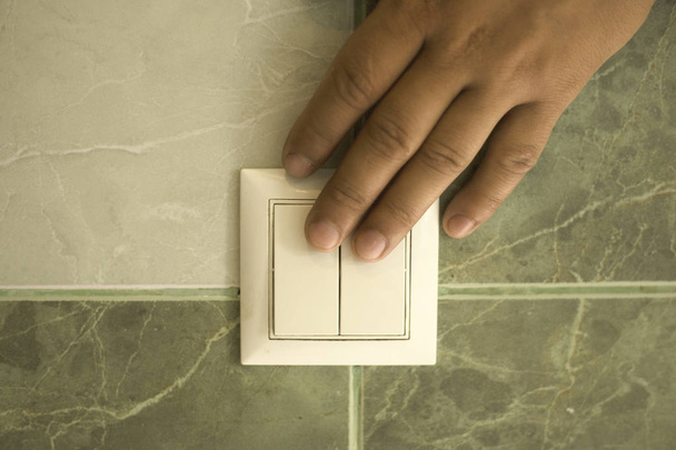 手は壁のスイッチを使用して浴室のライトを消す - 写真・画像