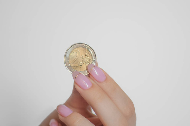 2 euro coin in female hand isolated on white background, money in fingers, gold and silver coin - Φωτογραφία, εικόνα
