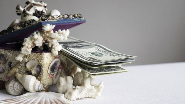 Empilement de billets de cent dollars dans une boîte de coquillages
 - Photo, image