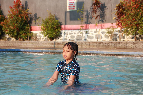 una niña jugando al agua en la piscina sintiéndose alegre, feliz y edificante
 - Foto, Imagen
