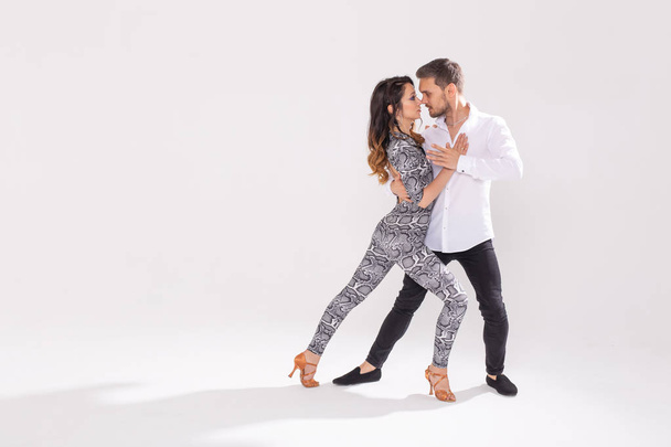Dança social, bachata, kizomba, zouk, conceito de tango - Homem abraça mulher enquanto dança sobre fundo branco com espaço de cópia
 - Foto, Imagem