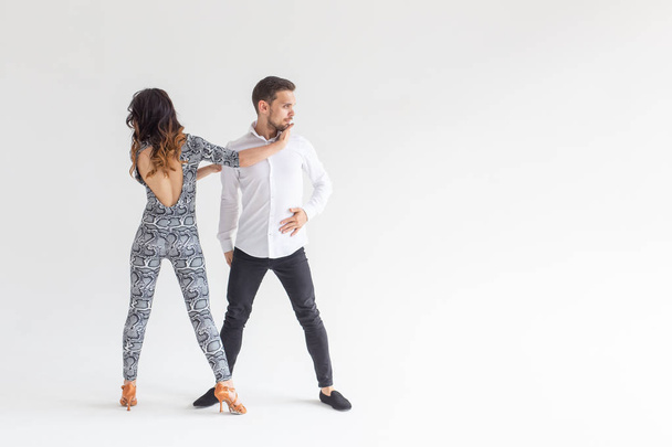 Baile social, bachata, kizomba, zouk, concepto de tango - Hombre abraza a mujer mientras baila sobre fondo blanco con espacio para copiar
 - Foto, imagen