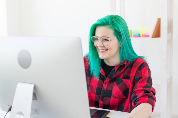 Εικονογράφος, γραφικός σχεδιαστής, εμψυχωτής και καλλιτέχνης concept-δημιουργός γυναίκα με όμορφα πράσινα μαλλιά και γυαλιά σχέδιο στο φορητό υπολογιστή - Φωτογραφία, εικόνα