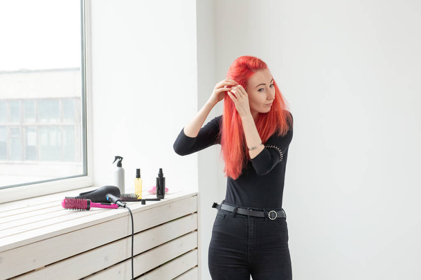 Όμορφη κοκκινομάλλα κορίτσι με μακριά μαλλιά, υφαίνει μια πλεξούδα, σε ένα σαλόνι ομορφιάς. Επαγγελματική περιποίηση μαλλιών και δημιουργία χτενίσματα. - Φωτογραφία, εικόνα