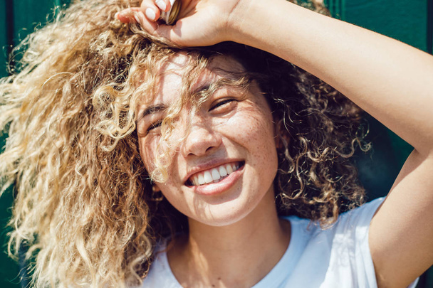 Portrait of a smiling young woman with curly hair and freckles. - Foto, immagini