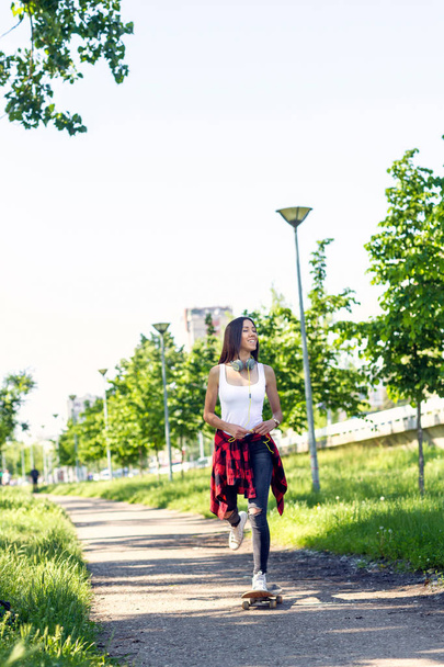 Smiling girl riding skateboards on city street - Foto, Bild