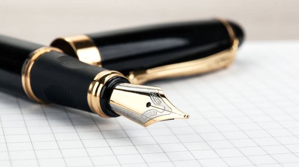 golden fountain pen on the notepad on a table  - Photo, Image