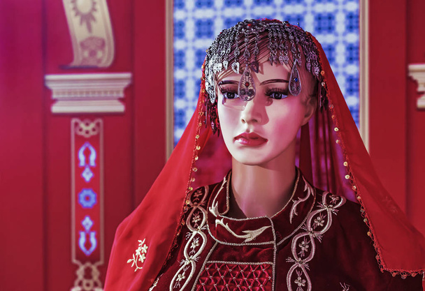 Female mannequin in oriental velvet dress on a red background. - Foto, Imagem