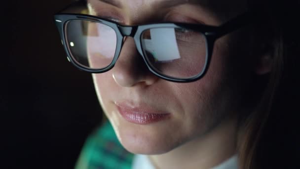 Woman in glasses looking on the monitor and surfing Internet. The monitor screen is reflected in the glasses - Footage, Video