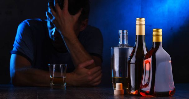 Butelki z napojami alkoholowymi i postacią pijanego człowieka - Zdjęcie, obraz