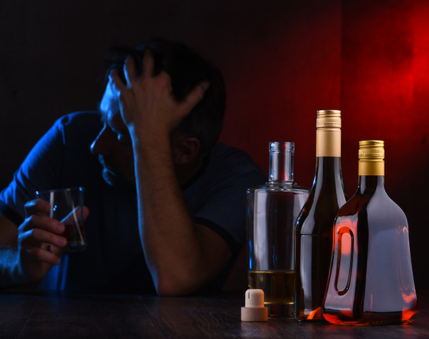 Garrafas com bebidas alcoólicas e a figura de um homem bêbado - Foto, Imagem
