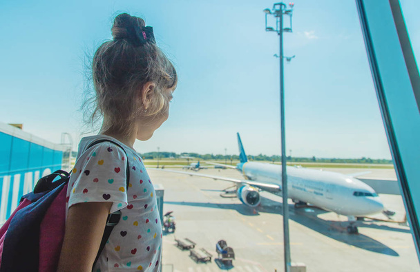 Een kind op de luchthaven op de achtergrond van het vliegtuig. Selectieve focus. - Foto, afbeelding