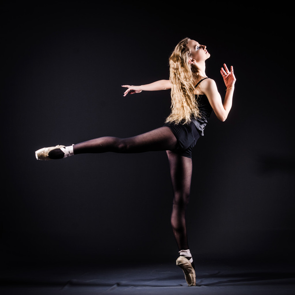 Ballerina dancing in the dark studio - Фото, зображення