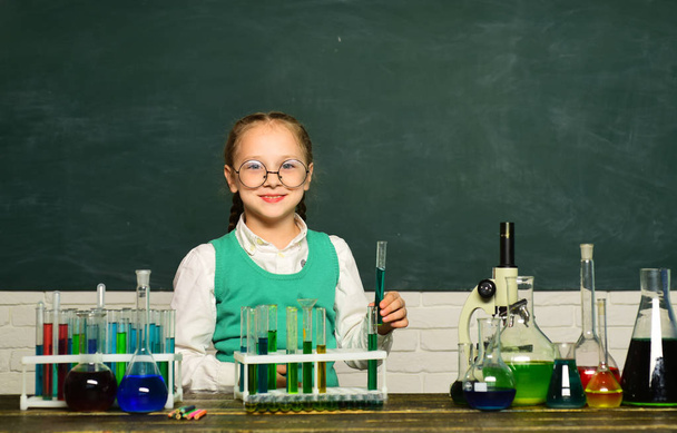 Back to school and home schooling. Kid is learning in class on background of blackboard. Biology experiments with microscope. Kid from primary school. - Foto, Imagen