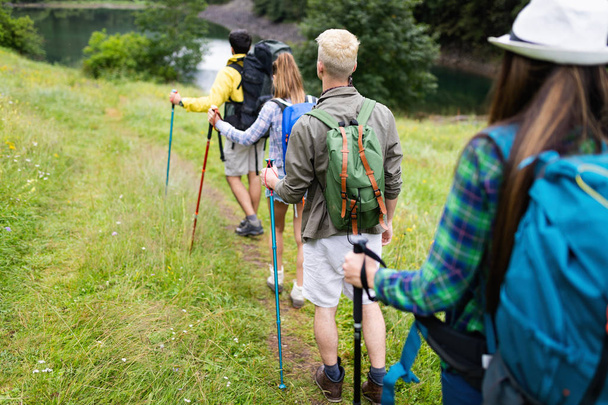 Group of friends with backpacks trekking together in nature - Fotografie, Obrázek