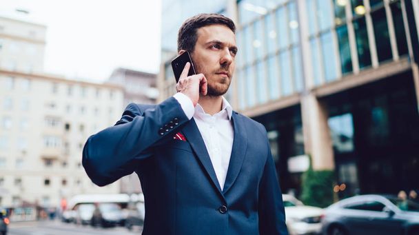 Serious male broker calling to secretary for online consultancy about financial exchange between entreprise corporations, man making cell conversation with partner discussing international meeting - Valokuva, kuva