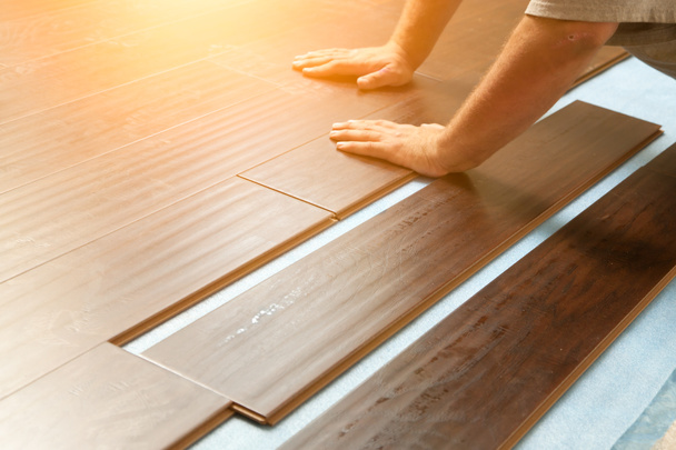 Homem instalando novo piso de madeira estratificada
 - Foto, Imagem
