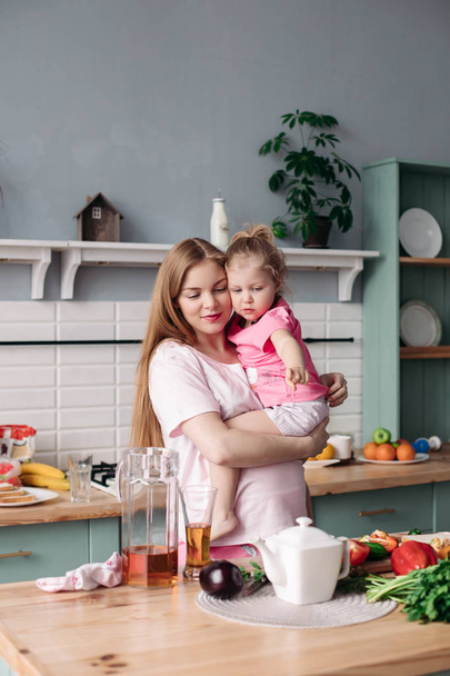 Happy beautiful mother with daughter in morning kitchen. - Photo, image
