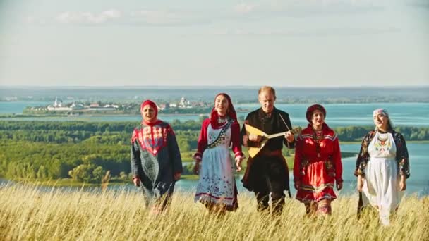 Lidé v tradičních ruských šatech, kteří chodí po hřišti a zpívají píseň - Záběry, video