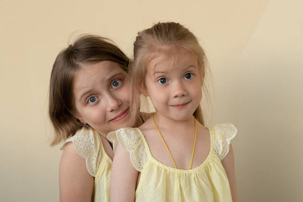 portrety dwóch małych dziewcząt stojących w żółte sukienki - Zdjęcie, obraz
