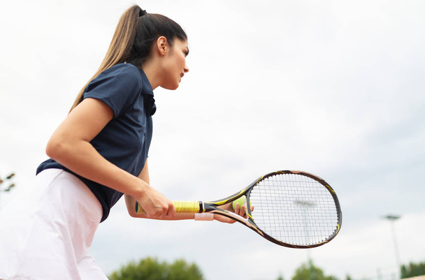 Young woman playing tennis at tennis court - 写真・画像