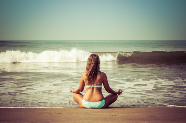 Jonge vrouw mediteert zittend op de Oceaan - Foto, afbeelding