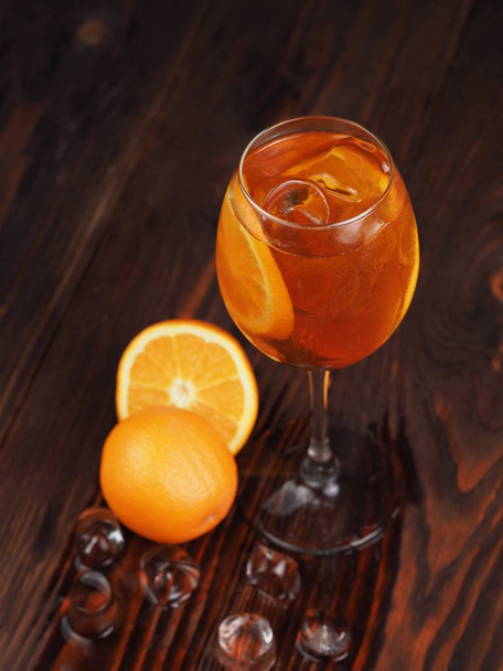 Orange cocktail with ice in a glass on a wooden surface - Foto, Bild