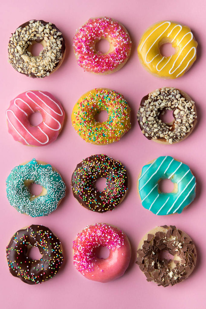 Kleurrijke zoete achtergrond. Heerlijke geglazuurde donuts op roze achtergrond.  - Foto, afbeelding
