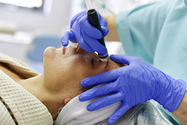 Skin care. Woman receiving facial beauty treatment. Facial therapy. Anti-aging procedures. - Фото, зображення