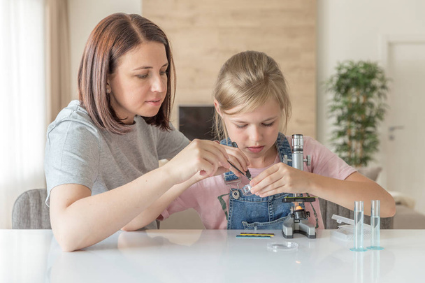 Mother and daughter make chemical experiments with microscope at home - Foto, Bild