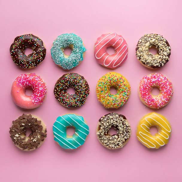 Colorful sweet background. Delicious glazed donuts on pink background.  - Foto, afbeelding