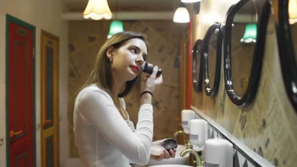 Mujer aplicando cosmética con un gran cepillo en el baño del albergue
 - Metraje, vídeo