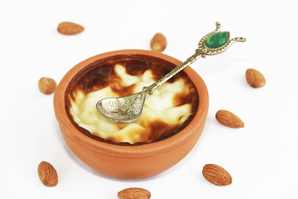 παραδοσιακό τουρκικό γλυκό πιάτο σε κεραμική πλάκα με κουτάλι διακόσμησης σε λευκό φόντο - Φωτογραφία, εικόνα