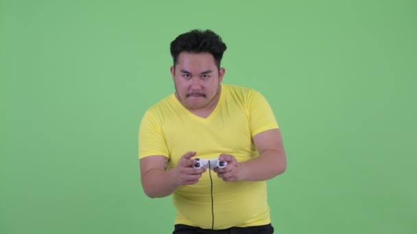 Happy young overweight Asian man playing games and winning - Footage, Video