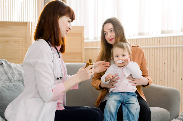Arzt gibt kleinen Mädchen einen Löffel Sirup - Foto, Bild