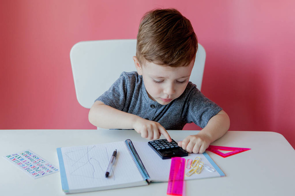 Portrait of cute kid boy at home making homework. Little concentrated child writing with colorful pencil, indoors. Elementary school and education. Kid learning writing letters and numbers - 写真・画像