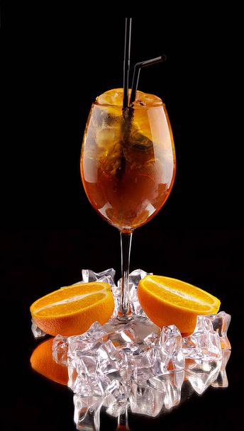 алкогольный коктейль на черном фоне со свежими летними фруктами и кубиками льда
 - Фото, изображение
