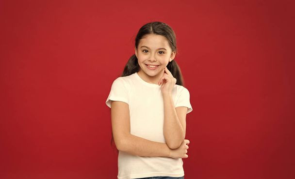 Feeling free and happy. Fashion girl on red background. Adorable girl child in casual style. Little kid with stylish long hair. Happy small child. Fashion look of small model. Little fashionista - Valokuva, kuva