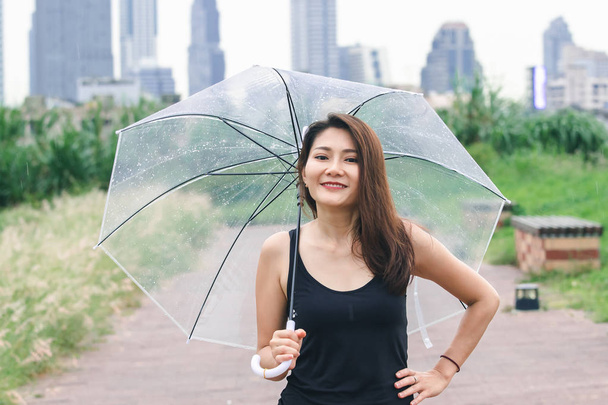 Naiset kävelevät sateenvarjolla polulla puistossa
 - Valokuva, kuva