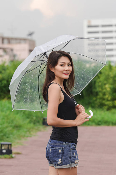 Naiset kävelevät sateenvarjolla polulla puistossa
 - Valokuva, kuva