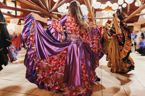 Beautiful gypsy girls dancing in traditional purple floral dress - Photo, Image