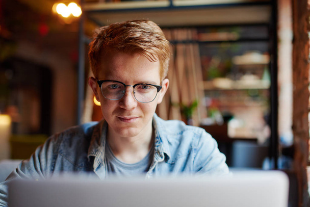 Fiatal férfi dolgozik a laptop a kávézóban. - Fotó, kép