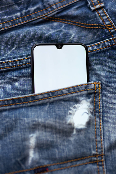 Moderne smartphone met wit scherm in blauwe jeans Pocket. - Foto, afbeelding