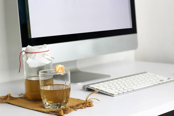 ферментований напій, цукровий чай здоровий натуральний пробіотик у скляній банці, зі склянкою та мандарином, готовим випити в офісі
 - Фото, зображення